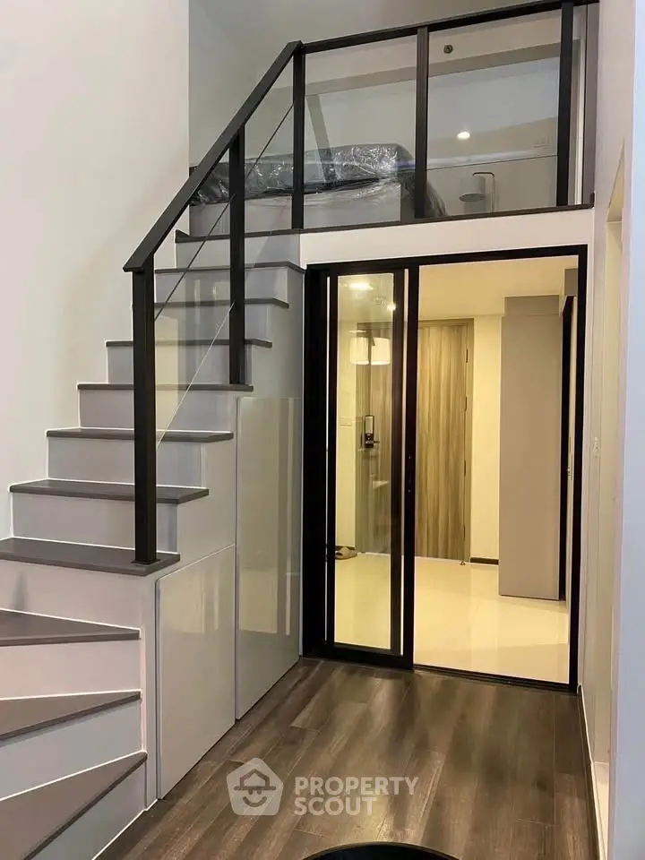 Modern duplex apartment with sleek staircase and glass partition, offering a stylish and contemporary living space.