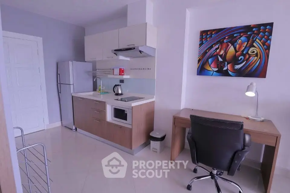 Modern kitchen with sleek appliances and stylish workspace in compact apartment.