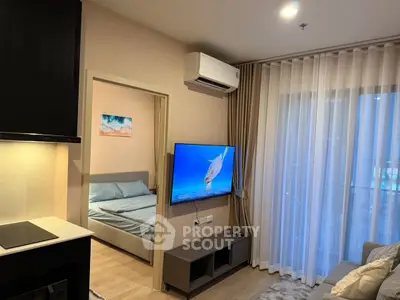 Modern living room with TV and view into cozy bedroom, featuring elegant curtains and air conditioning.