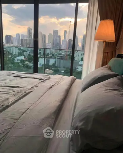 Luxurious bedroom with stunning city skyline view from large windows.