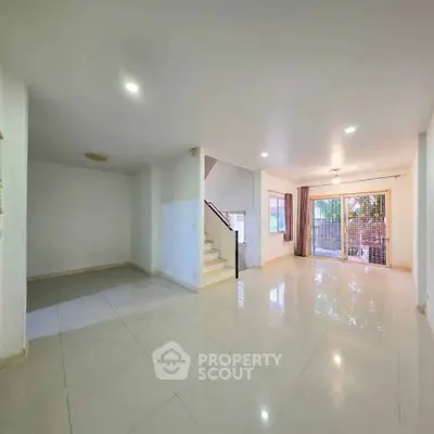 Spacious modern living room with glossy tiled floors and large windows for natural light.