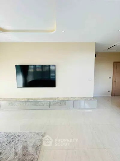 Spacious modern living room with wall-mounted TV and sleek storage unit.