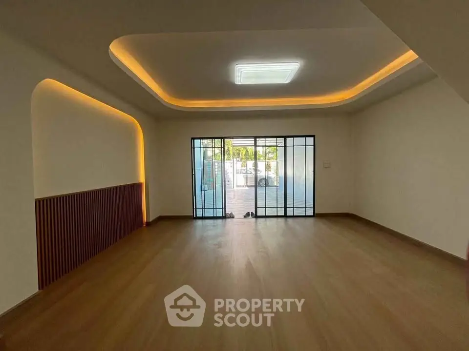 Spacious modern living room with stylish lighting and large glass doors opening to a garden.