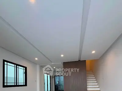 Modern interior with sleek staircase and recessed lighting in a spacious living area.