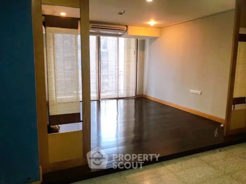 Spacious living room with wooden flooring and large windows for natural light.