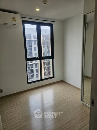 Modern empty bedroom with large window and mirrored closet in urban apartment