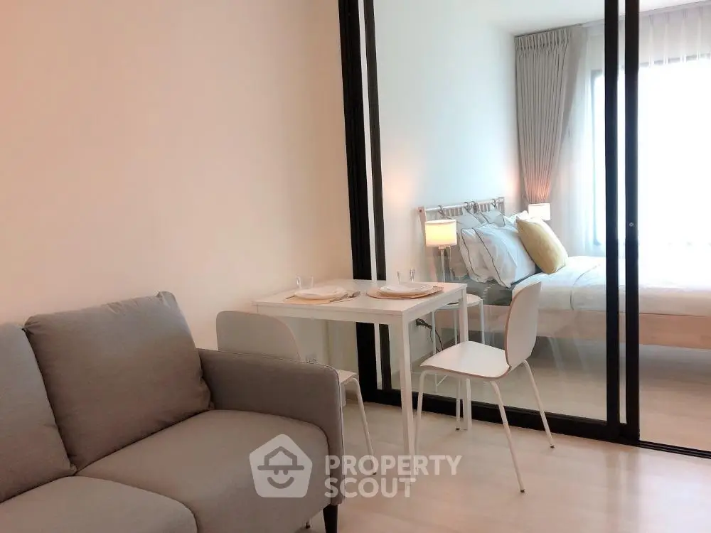 Modern studio apartment with cozy living area and bedroom separated by glass partition.