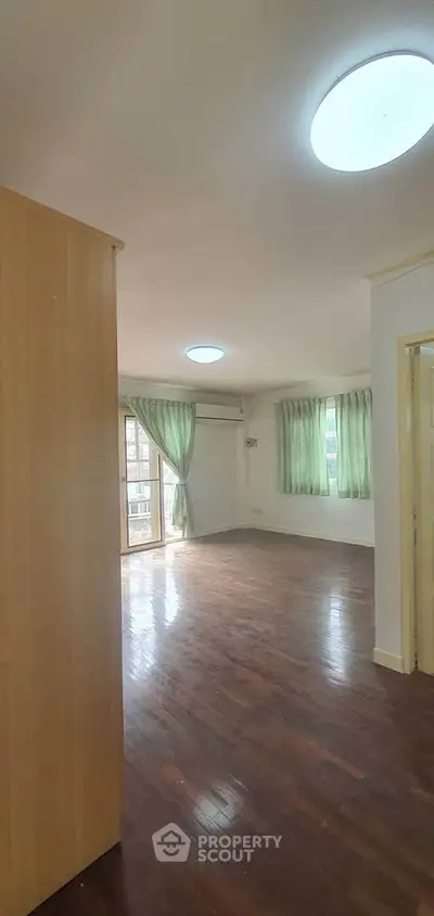 Spacious living room with wooden floors and large windows for natural light