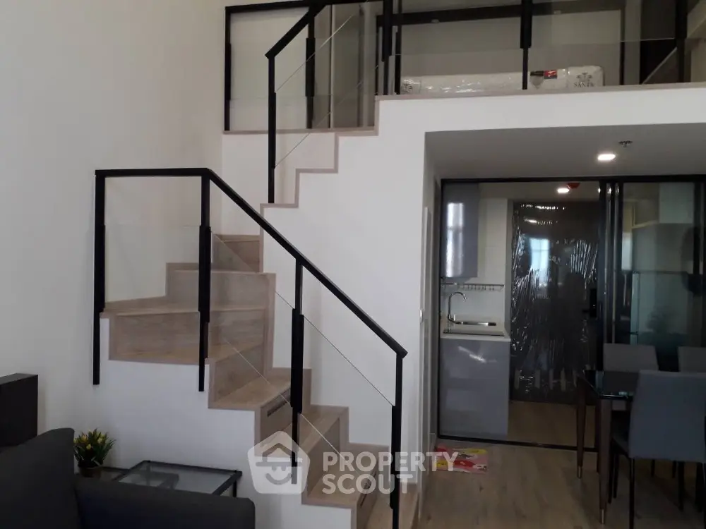 Modern duplex apartment with stylish floating staircase and integrated kitchen, showcasing a sleek design and open-plan living space.
