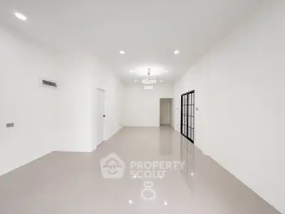 Spacious minimalist living room with modern lighting and sleek tile flooring.