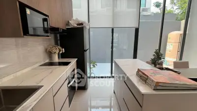 Modern kitchen with sleek cabinetry, marble countertops, and large windows for natural light.