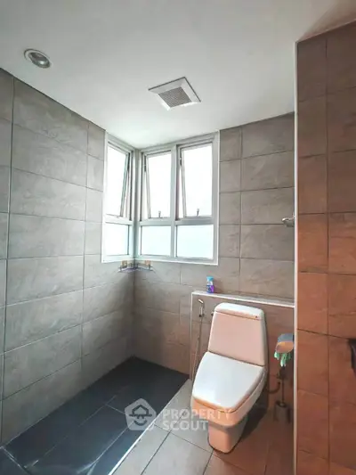 Modern bathroom with sleek tiles and natural light from large windows.