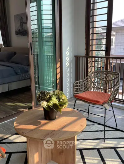 Charming bedroom with balcony access, featuring cozy seating and natural light for a serene retreat.