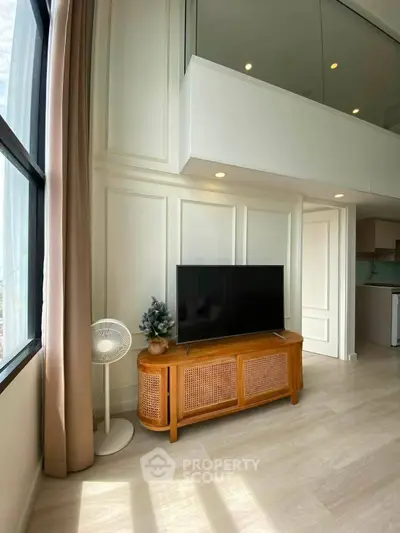 Modern living room with stylish TV stand and large window, showcasing bright and airy interior design.