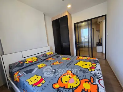 Modern bedroom with playful cartoon-themed bedding and sliding glass doors leading to a study area.