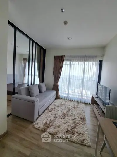 Modern living room with large windows and cozy decor in a high-rise apartment.