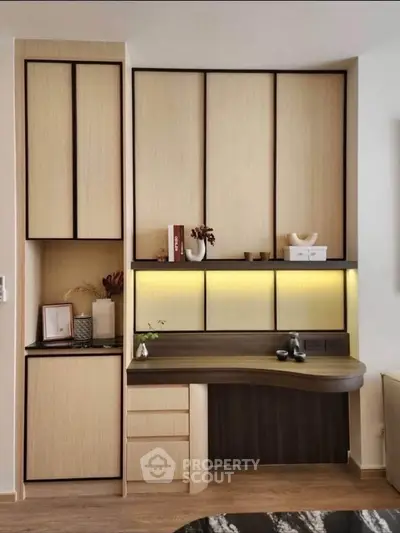 Modern study area with built-in desk and cabinets, featuring elegant lighting and decor.