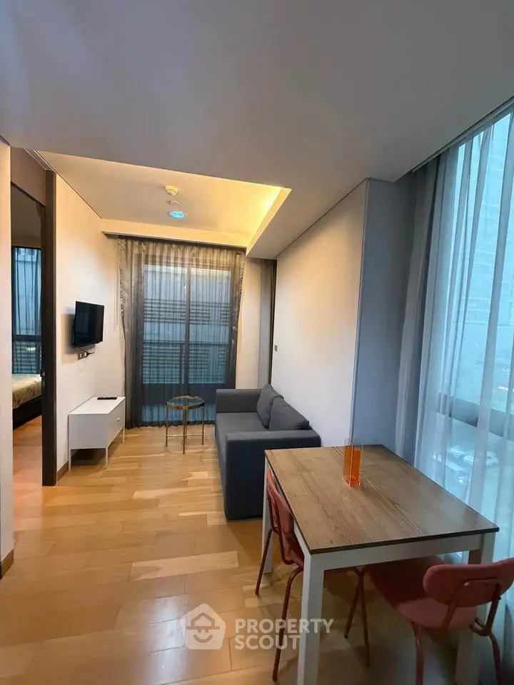 Modern living room with wooden flooring, cozy sofa, and dining table in a stylish apartment.