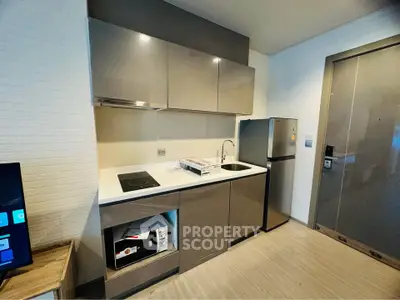 Modern compact kitchen with sleek cabinets and stainless steel appliances in a stylish apartment.