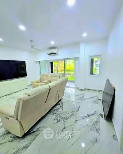 Spacious modern living room with marble flooring and large TV setup.