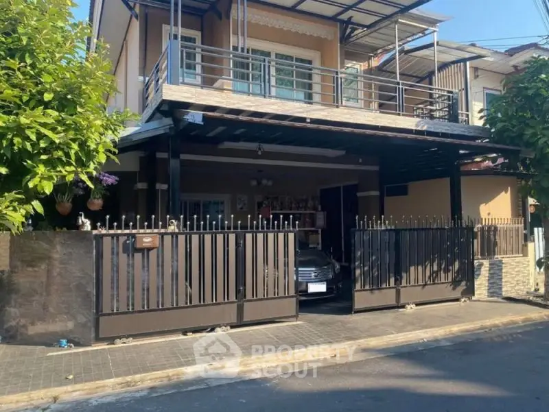 Charming two-story house with gated driveway and balcony in a suburban neighborhood.
