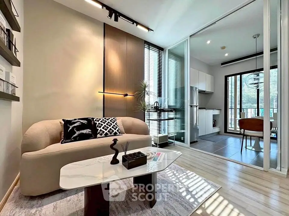 Modern living room with elegant decor and open kitchen layout, featuring stylish furniture and natural light.