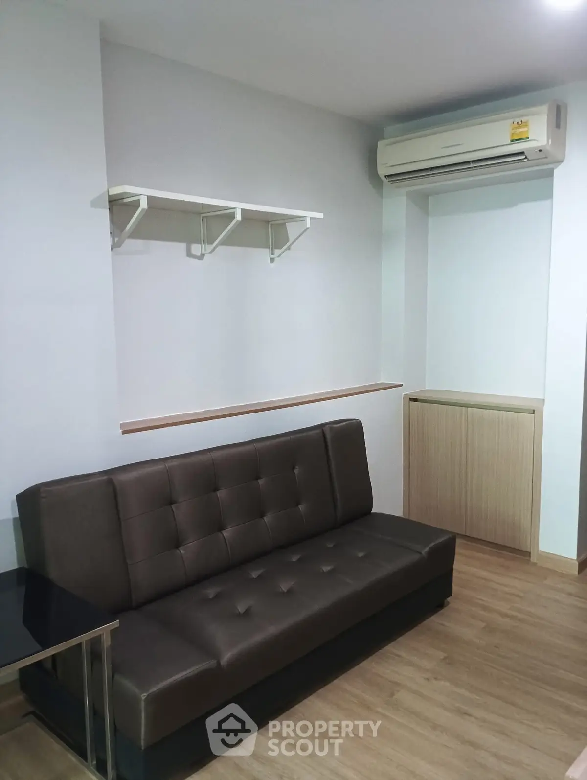 Modern living room with sleek brown sofa and wall-mounted air conditioner in a cozy apartment.