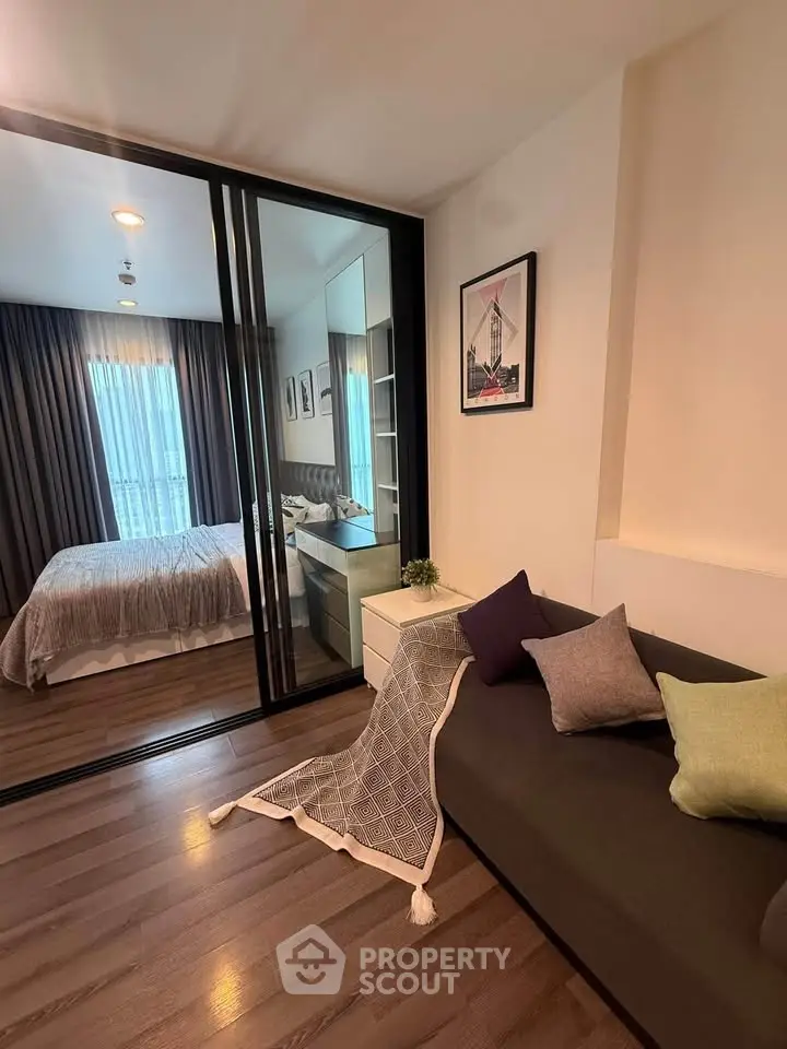 Modern apartment interior with cozy living room and stylish bedroom separated by glass partition.