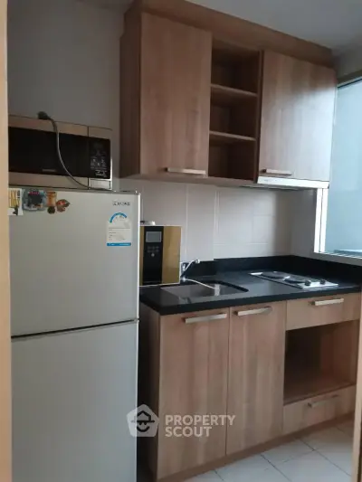 Modern kitchen with wooden cabinets and sleek appliances in a cozy apartment.