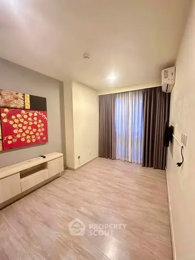 Spacious living room with modern decor and large window, perfect for relaxation and entertainment.