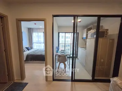 Modern apartment with open kitchen and cozy bedroom, featuring sleek design and natural light.