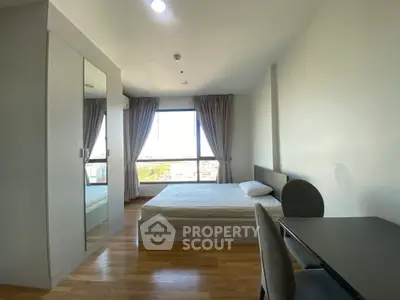 Spacious bedroom with large window and modern furnishings in a high-rise apartment.