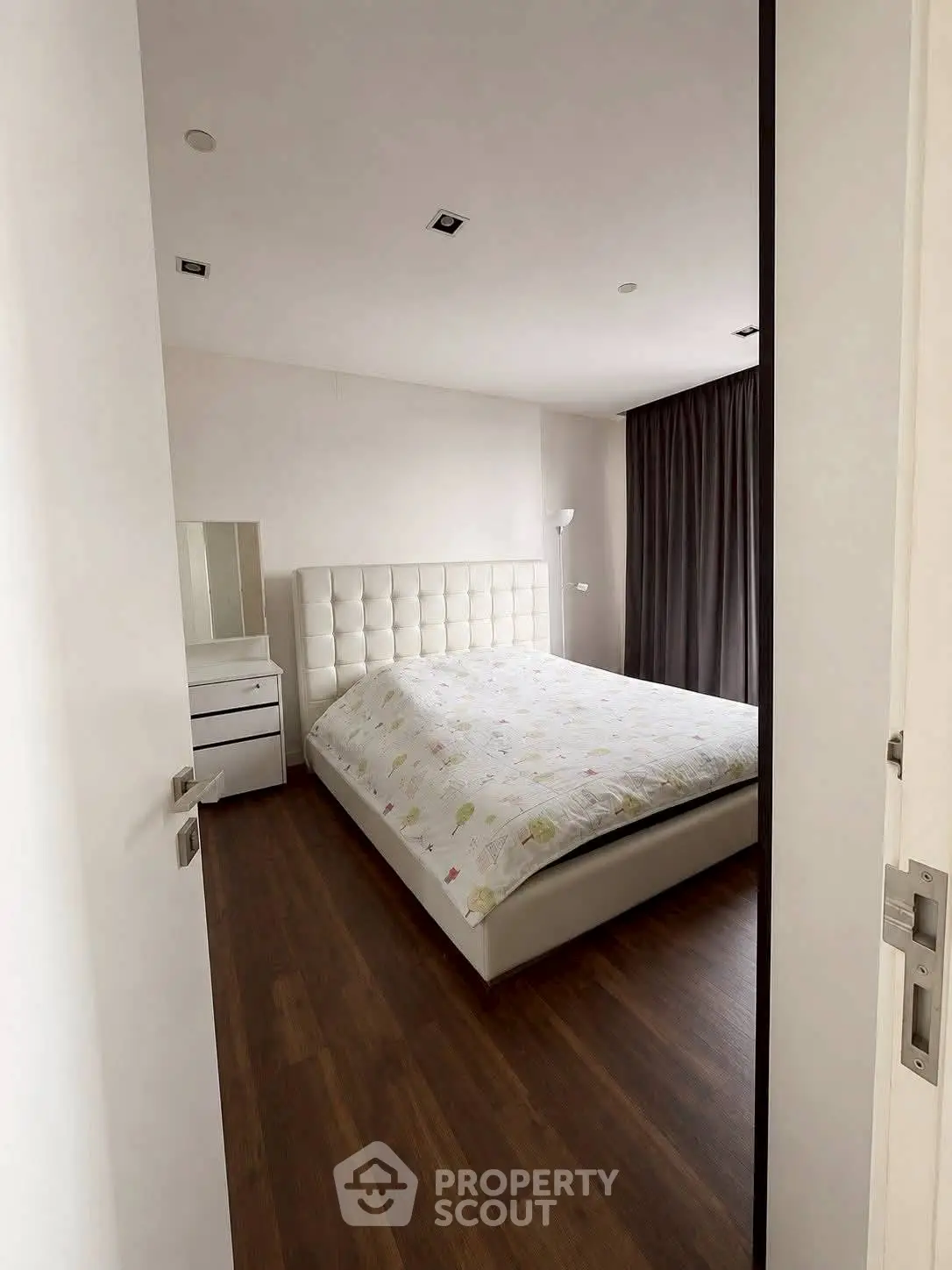 Modern bedroom with elegant decor and wooden flooring, featuring a plush bed and stylish curtains.