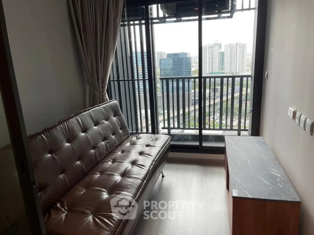 Modern living room with leather sofa and city view balcony in high-rise apartment.