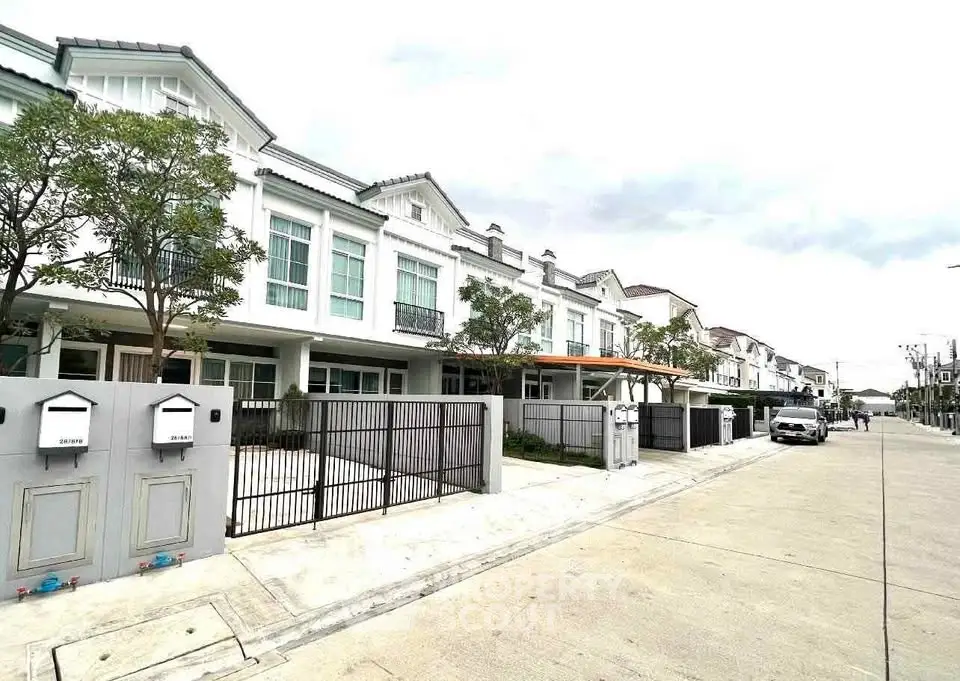 Modern townhouse exterior with gated entrance and driveway in a suburban neighborhood.