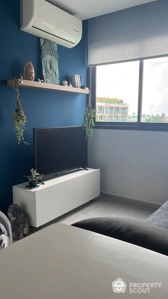 Chic modern bedroom with a serene blue color scheme, featuring a sleek low-profile bed, stylish decor, and a large window inviting ample natural light.