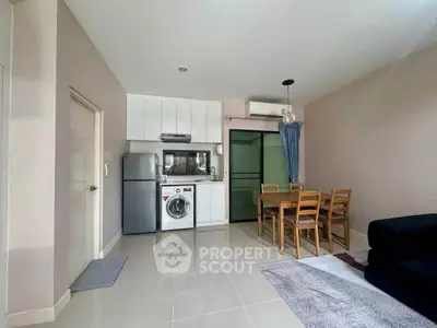 Modern kitchen and dining area with washing machine and fridge in open layout apartment.