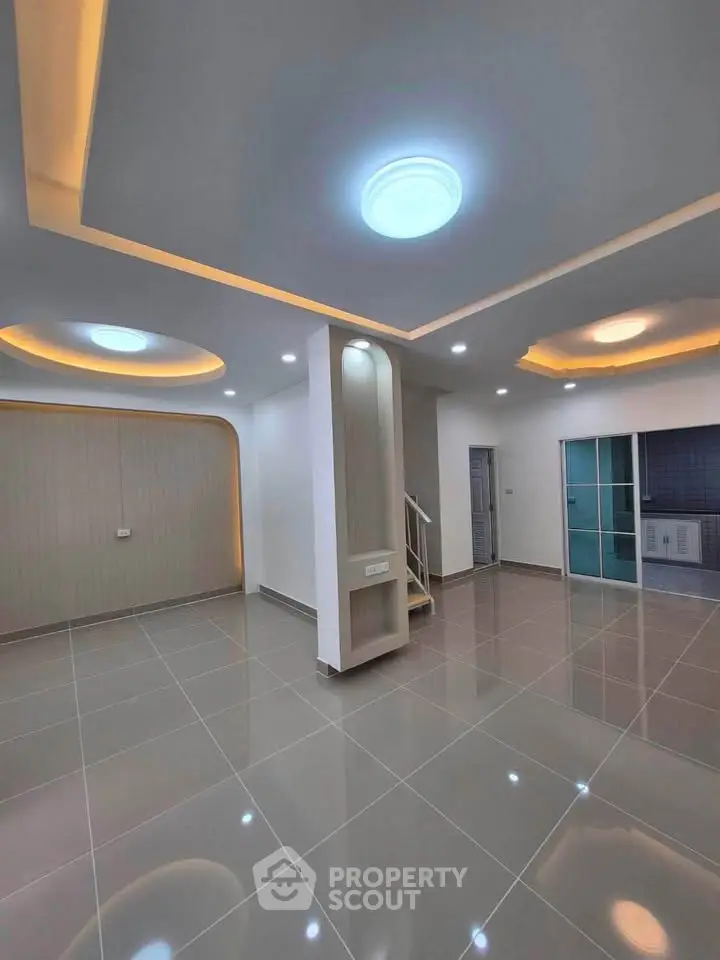 Spacious modern living room with elegant ceiling lights and sleek tile flooring.