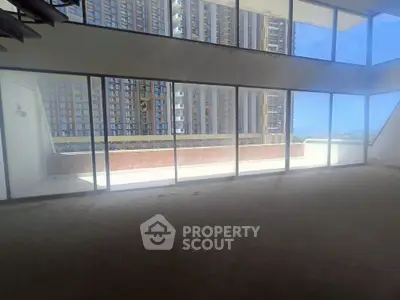 Spacious modern apartment with floor-to-ceiling windows and expansive balcony offering stunning city views.