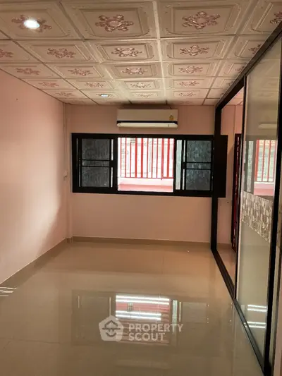 Spacious room with glossy tiled floor and decorative ceiling in modern apartment.