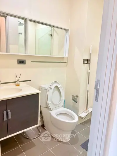 Modern bathroom with sleek fixtures and neutral tones, featuring a toilet and vanity with mirror.