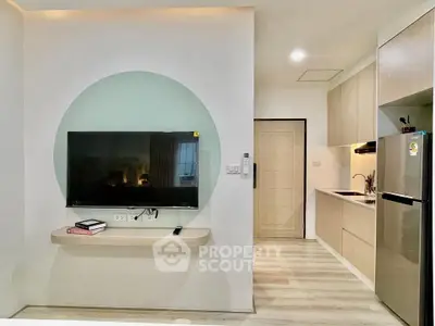 Modern living room with wall-mounted TV and sleek kitchen area
