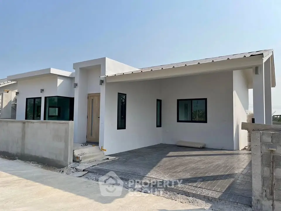 Modern single-story white house with minimalist design and spacious driveway.