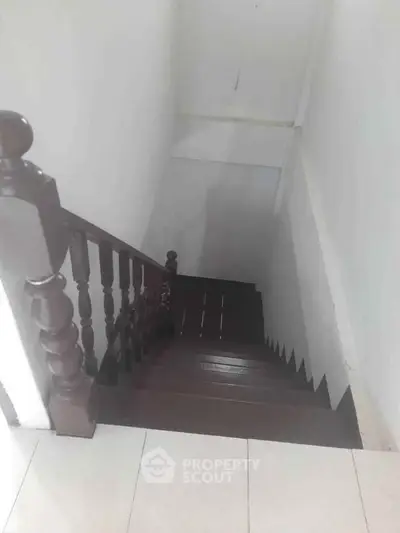 Charming wooden staircase with classic railing in a cozy home setting.