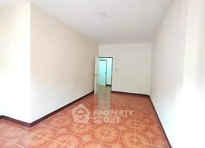 Spacious empty room with tiled flooring and open door, ideal for customization.
