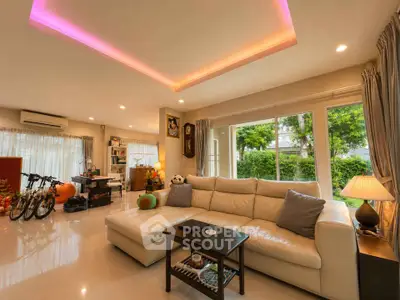 Spacious living room with modern decor and large windows overlooking greenery.
