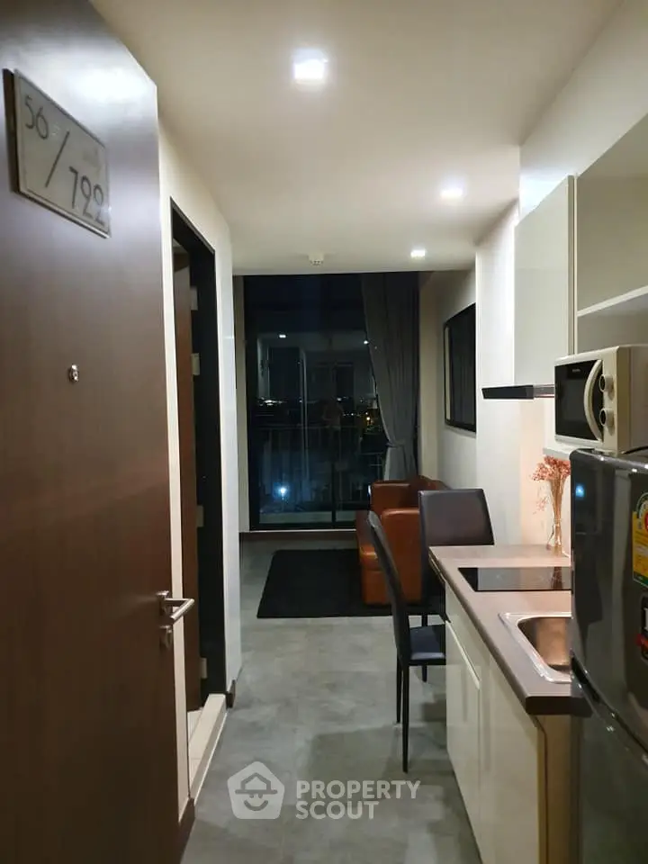 Modern apartment entrance with sleek kitchen and cozy living area, offering a stunning city view.