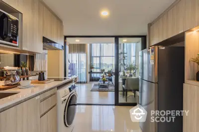 Modern kitchen with sleek cabinetry and integrated appliances, leading to a bright living area with floor-to-ceiling windows.