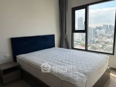 Modern bedroom with city view and large window, featuring a comfortable bed and stylish decor.