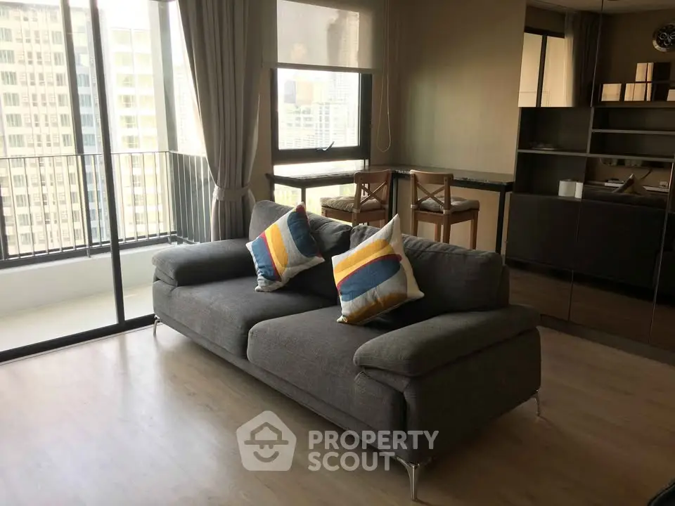 Modern living room with stylish sofa and city view balcony in high-rise apartment.